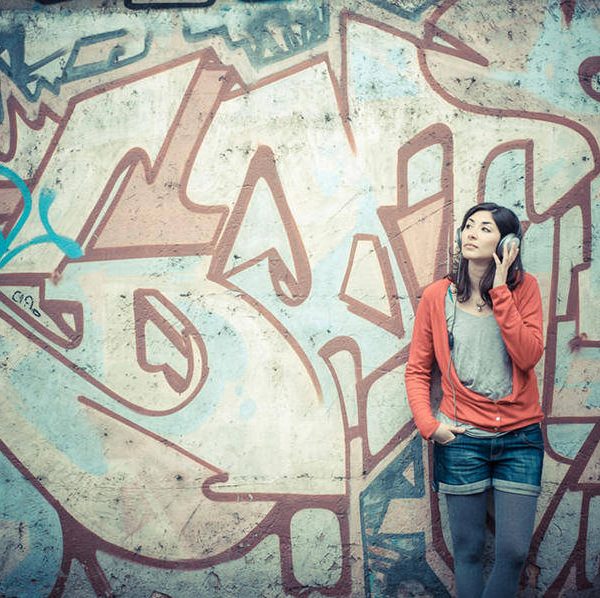 Beautiful stylish woman listening to music in the street