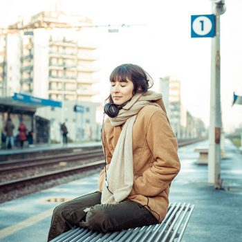 beautiful young woman listening to music headphones  in the city winter
