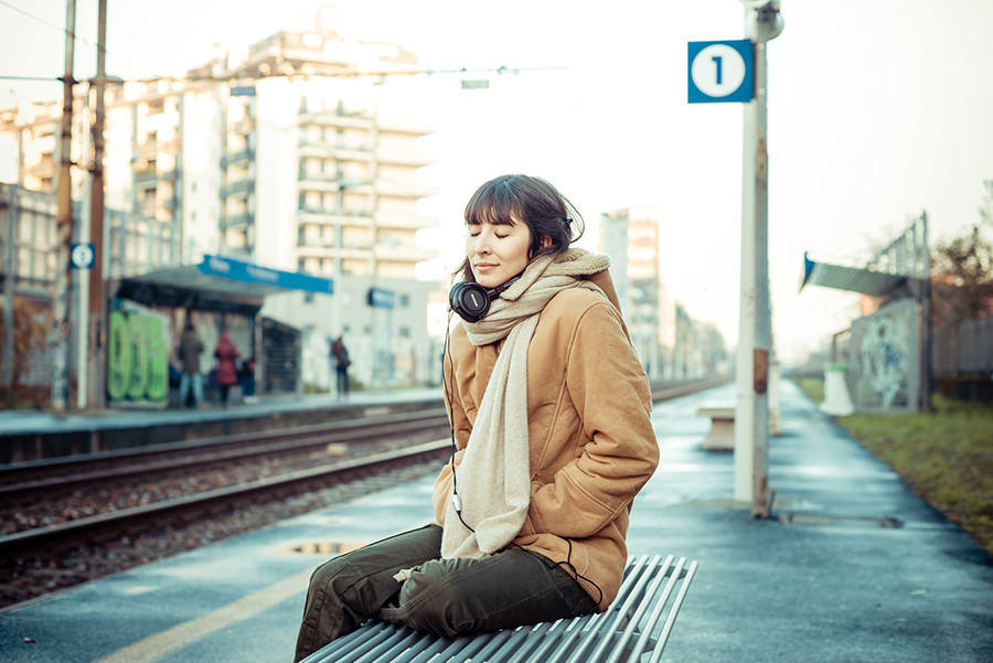 beautiful young woman listening to music headphones  in the city winter