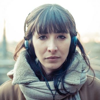 beautiful young woman listening to music headphones  in the city winter