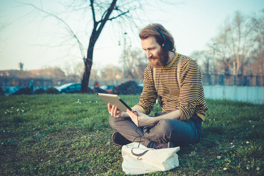 young bearded stylish handsome hipster man using tablet outdoors