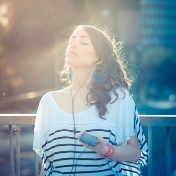 young beautiful brunette woman with smart phone listening music  in the city