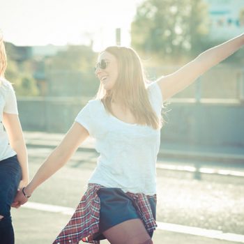 two beautiful young women jumping and dancing in the city