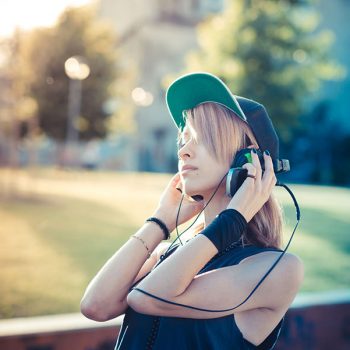 young beautiful model woman listening music in the city