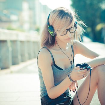 young beautiful model woman listening music in the city